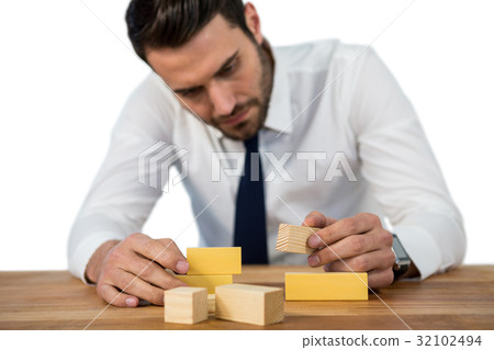 Businessman placing wooden block on a tower Businessman placing wooden block on a tower 32102494