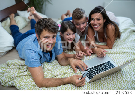 Family doing online shopping on laptop in bedroom at home 32102558
