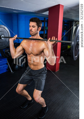 Man exercising with barbell in fitness studio Man exercising with barbell in fitness studio 32102589