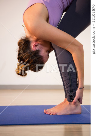 Woman performing standing forward bend 32102670