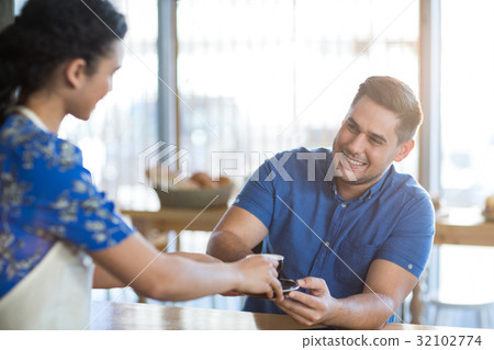 Waitress serving a cup of coffee to customer Waitress serving a cup of coffee to customer 32102774