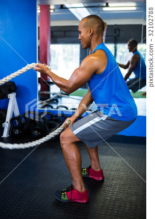 Male athlete exercising with ropes in gym Male athlete exercising with ropes in gym 32102788