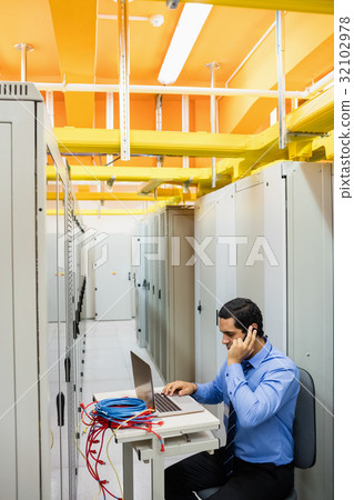 Technician talking on mobile phone in server room 32102978