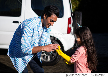 Father helping daughter to wear gloves 32102983