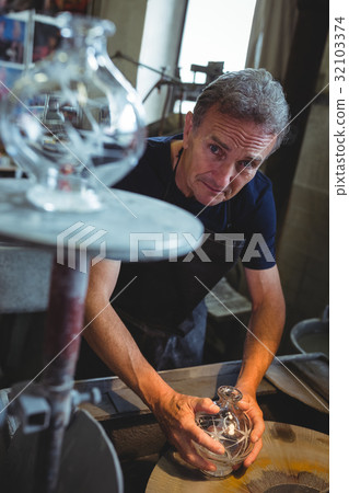 Glassblower working on a glass at glassblowing factory 32103374