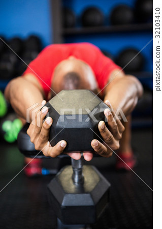 Athlete exercising with dumbbell on bench Athlete exercising with dumbbell on bench 32103410
