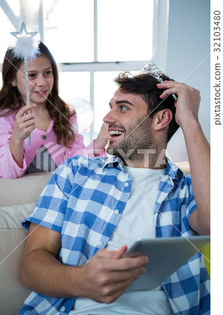 Girl dressed up in a fairy costume placing tiara on fathers head 32103480