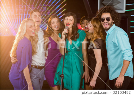 Group of friends singing song together in bar 32103492