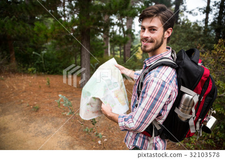 Male hiker holding a map in forest Male hiker holding a map in forest 32103578