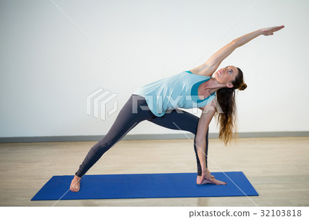 Woman performing extended side angle pose on exercise mat 32103818