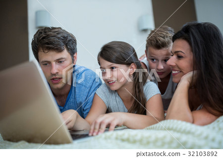 Happy family using laptop in bedroom Happy family using laptop in bedroom 32103892