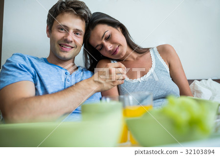 Smiling couple having breakfast on bed Smiling couple having breakfast on bed 32103894