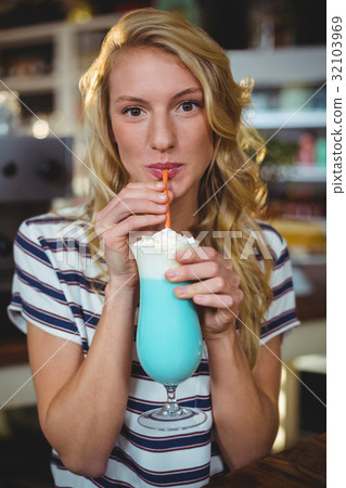 Portrait of woman drinking milkshake with a straw 32103969