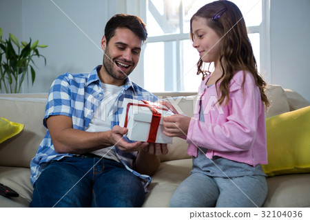 Father giving gift to daughter in the living room Father giving gift to daughter in the living room 32104036