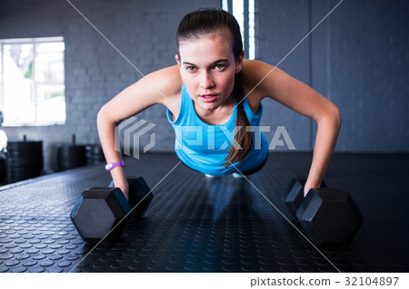 Sporty woman doing push-ups with dumbbells Sporty woman doing push-ups with dumbbells 32104897