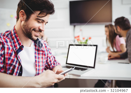 Happy executive texting in meeting at creative office 32104967