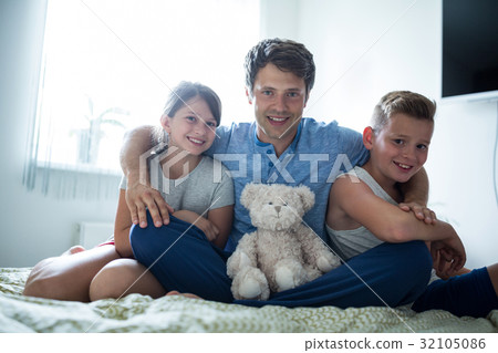 Portrait of father and kids sitting in bedroom 32105086