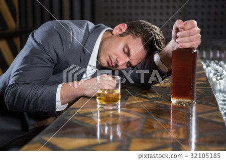Drunk man lying on a counter with bottle of whisky 32105185