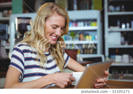 Woman using digital tablet while having cup of coffee 32105271