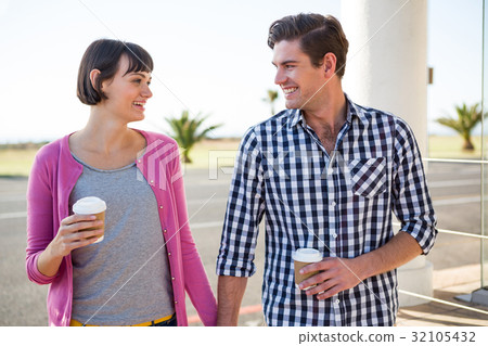 Couple with coffee cups walking together 32105432