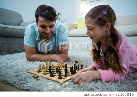 Father and daughter playing chess in the living room Father and daughter playing chess in the living room 32105810