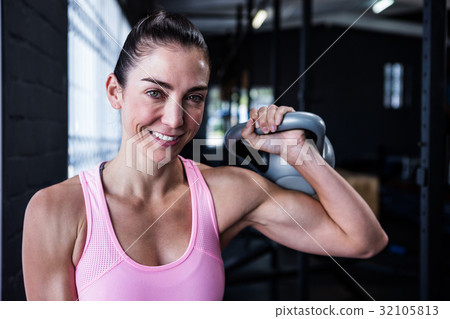 Smiling female athlete lifting kettlebell Smiling female athlete lifting kettlebell 32105813