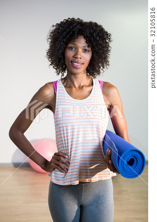 Portrait of smiling woman holding exercise mat Portrait of smiling woman holding exercise mat 32105816