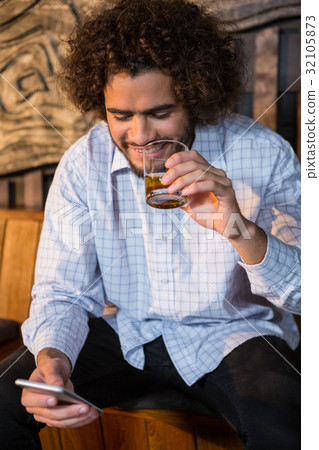 Man using mobile phone while having whisky 32105873