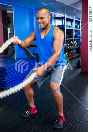 Athlete exercising with ropes in fitness studio 32106174