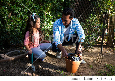 Father and daughter potting a plant in pot at backyard 32106205