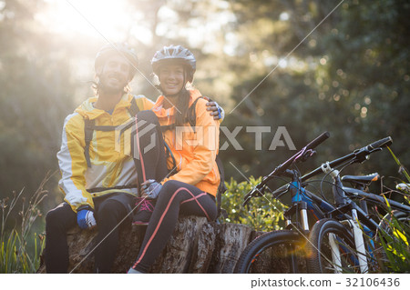 Biker couple sitting on a tree stump 32106436