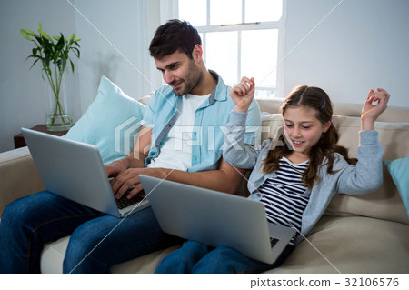 Father and daughter using laptop in the living room 32106576