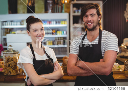 Waiter and waitress standing with arms crossed in cafe 32106666