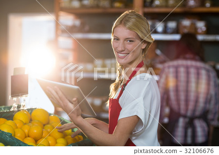Smiling staff using digital tablet while checking fruits in organic section 32106676