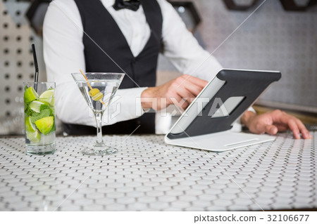 Bartender using digital tablet at bar counter 32106677