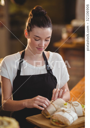 Smiling waitress standing at counter with sandwiches 32106906