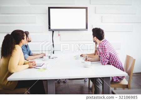 Partners looking at television in creative office 32106985