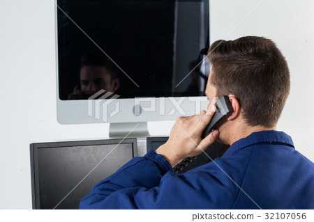 Security officer talking on telephone while looking at computer monitors 32107056