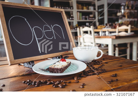 Open signboard with slice of cake and coffee cup on a table 32107167