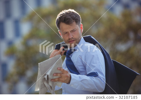 Handsome businessman reading newspaper Handsome businessman reading newspaper 32107185