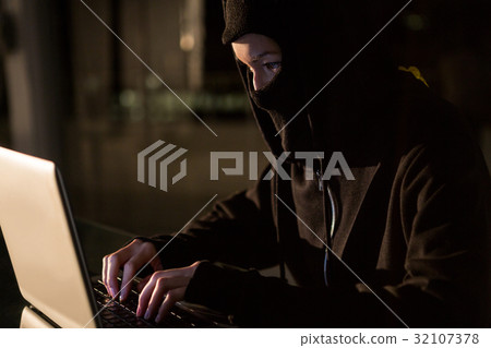 Woman in balaclava using laptop Woman in balaclava using laptop 32107378