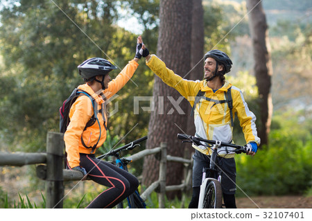 Biker couple giving high five to each other in countryside Biker couple giving high five to each other in countryside 32107401