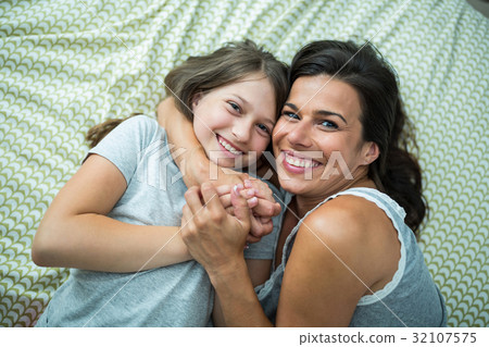 Mother and daughter playing on bed at home 32107575
