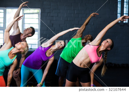 Athletes bending while exercising in gym 32107644