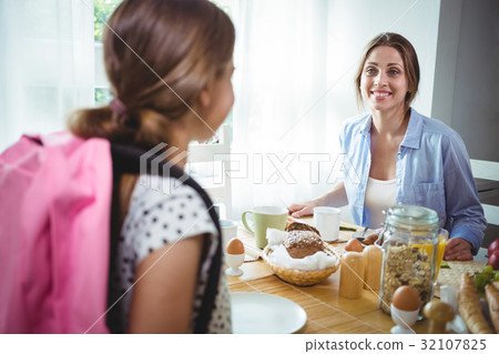 Mother interacting with her daughter while having breakfast 32107825