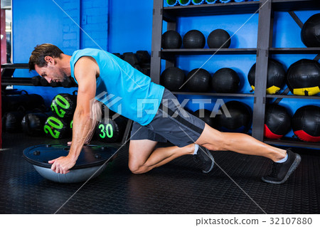 Young man using BOSU ball in gym Young man using BOSU ball in gym 32107880