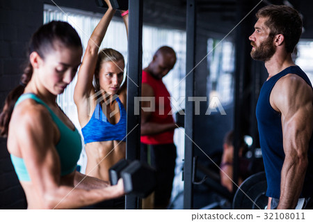 Friends lifting dumbbells while working out 32108011
