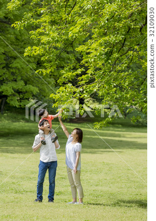 Three-person family playing in a fresh green park 32109030