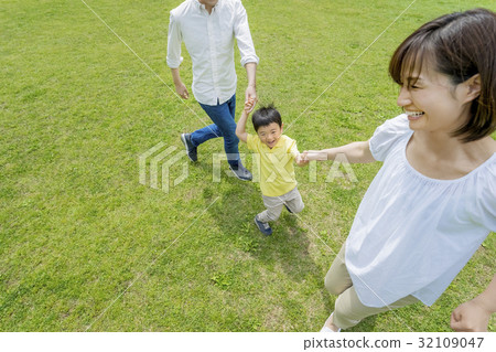 Three-person family playing in a fresh green park 32109047