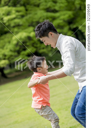 Father and son playing in a fresh green park 32109049